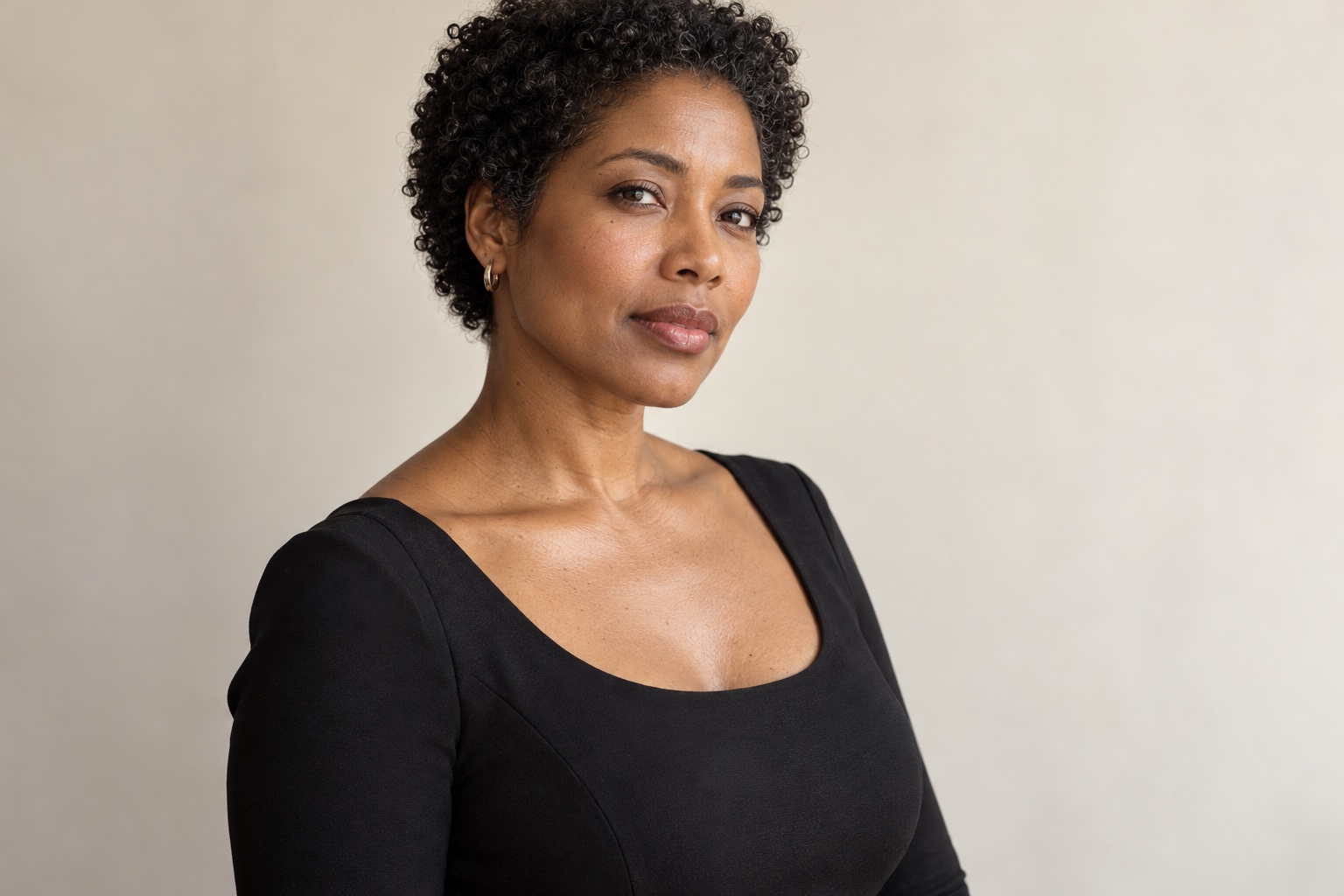Portrait généré par IA d’une femme adulte portant un haut noir sobre ; épaules et haut du décolleté visibles sur un fond de studio ivoire.